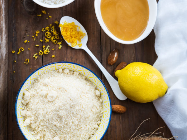 Ingredients for Healthy Vegan Coconut and Lemon Truffles such as Ground Almonds, Desiccated Coconut, Lemon Zest, Honey on Rustic Tray