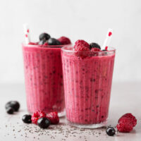 Tasty healthy dieting red berry smoothie with chia seeds in glasses on grey background.